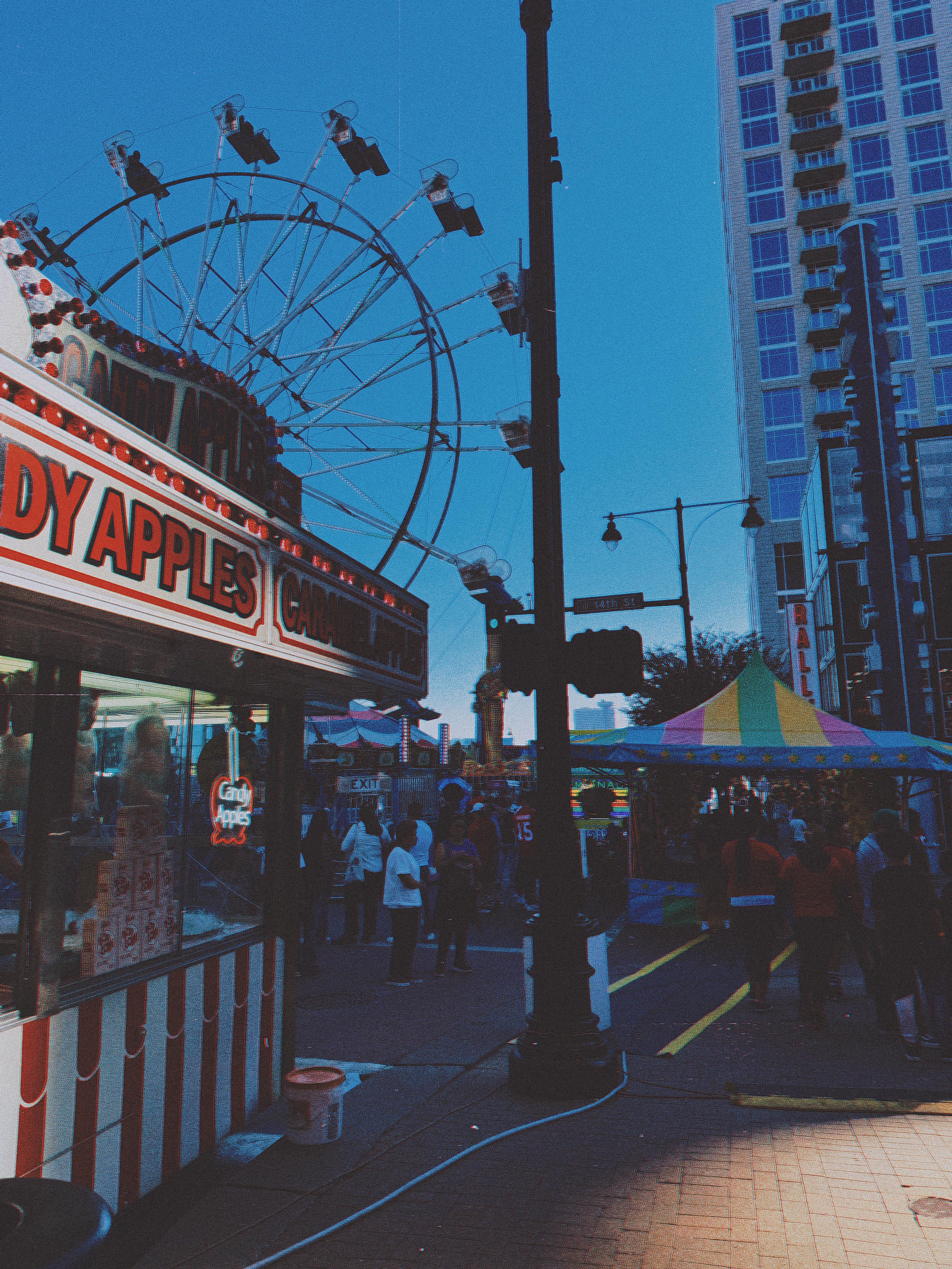 candy apple stand with high rise building in the background and ferris wheel