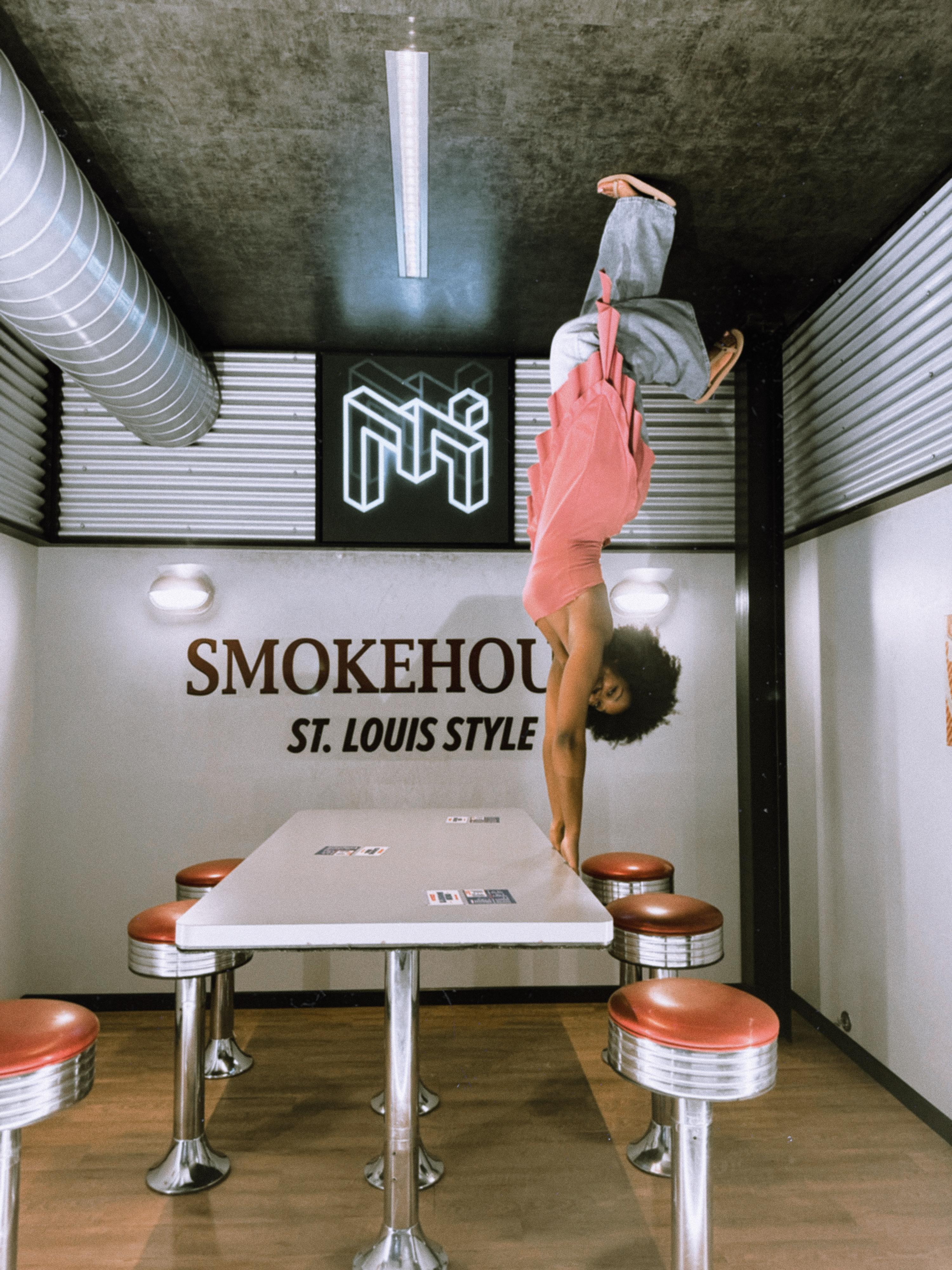 shows a woman hanging upside down, holding on to a table